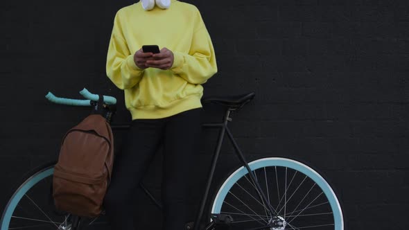 Transgender adult with a bike and using a phone