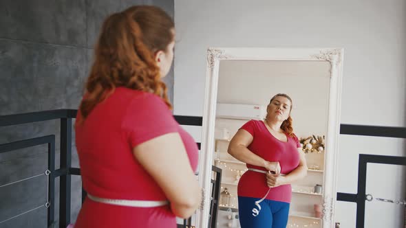 Young Plus Size Lady Measuring Waist with Tape Disappointed Because of Big Result