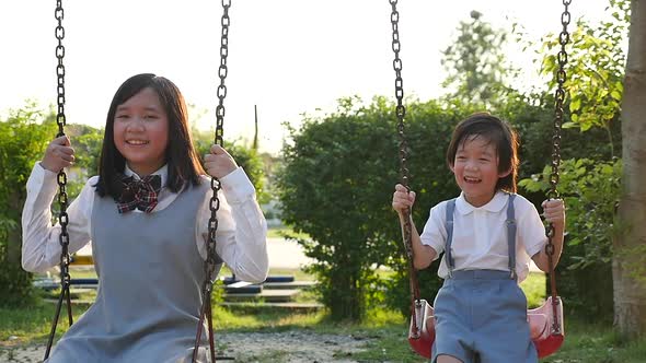 Asian Girl And Her Brother Playing Swing Together In The Park Slow Motion