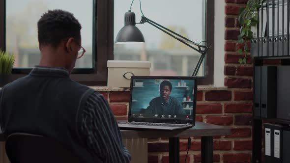 Startup Employee Using Remote Video Call on Laptop to Talk to Colleague