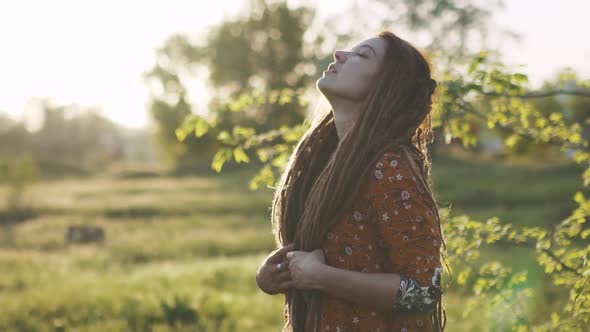 Portrait of an Beautiful Hippie Woman with Dreadlocks in the Woods at Sunset Having Good Time