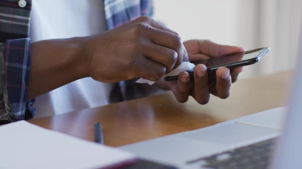 Mid section of man wiping his smartphone with a tissue