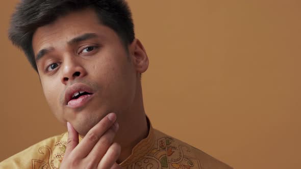 Handsome Indian man in national cloth looking at his skin at the camera