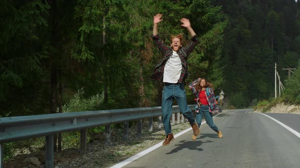 Overjoyed Hitchhikers Waving Hands on Mountain Road