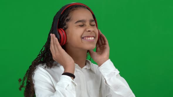 Portrait of Happy Carefree African American Teen Girl Enjoying Music in Headphones Dancing on Green