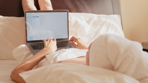 Woman Wrapped in Bath Towel Using Laptop on Comfy Bed