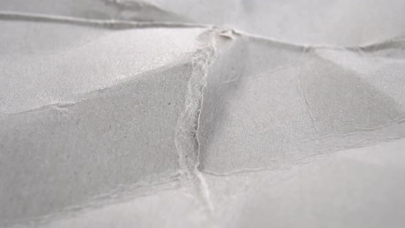 Torn wrinkled texture gray wrapping paper. Ragged edges of grey crumpled cardboard. Macro