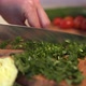 Woman's Hands Cutting a Fresh Dill and Parsley on Wooden Cutting Board Using Kitchen Knife - VideoHive Item for Sale