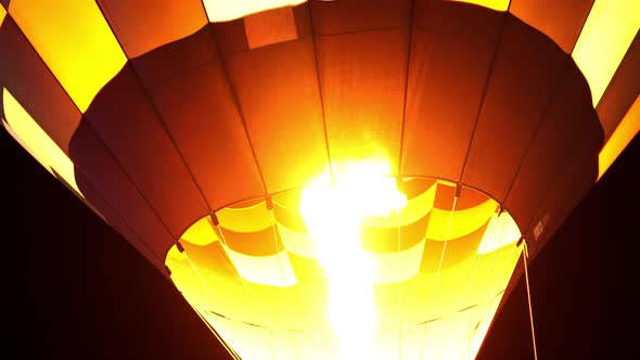 close up of hot air balloon with burner flame glowing at a night