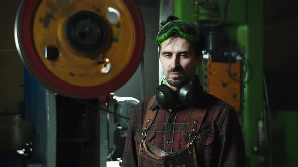 A Man in Overalls Stands in a Workshop