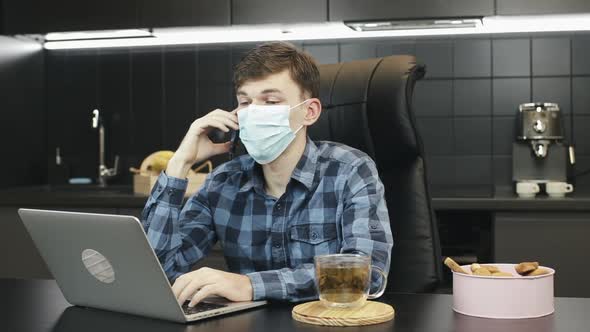 Man in protective face mask making phone call from home. Working from home concept