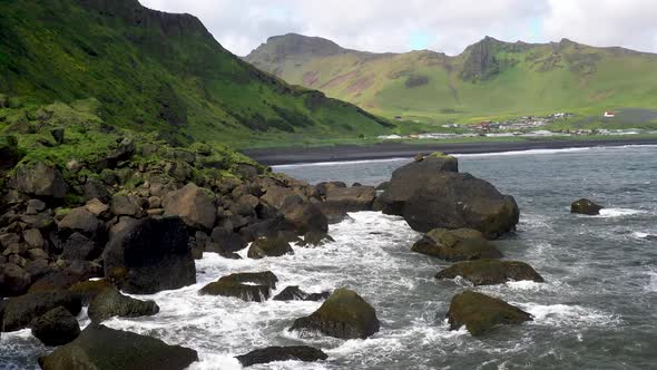 Vik, Iceland coast with waves crashing on rocks with drone video moving forward through rocks.