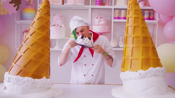 Young man dressed as chef greedily biting cake, standing in bright confectionery. 