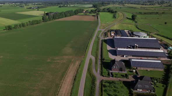 Large farm with solar panels in Dutch river valley landscape seen from above following the embankmen