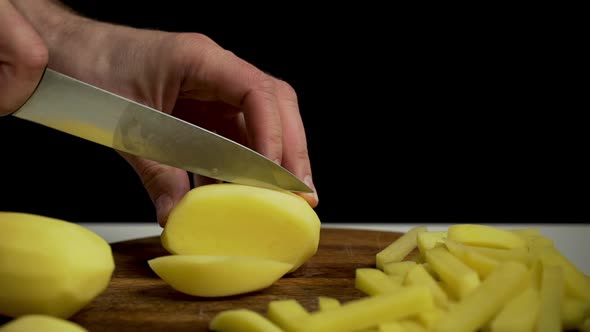 Close-up of hands slicing russet potatoes