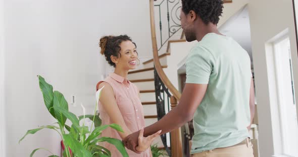 Happy biracial couple hugging with joy in new house