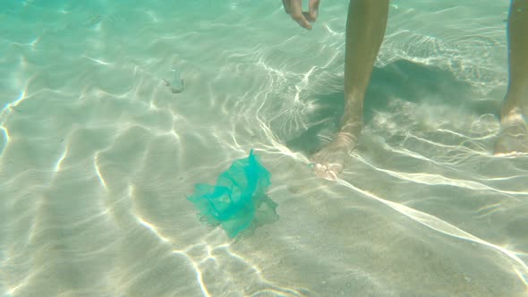 Underwater Shot of a Man That Collects Plastic Bags in the Beautiful Turquoise Sea. Paradise Beach