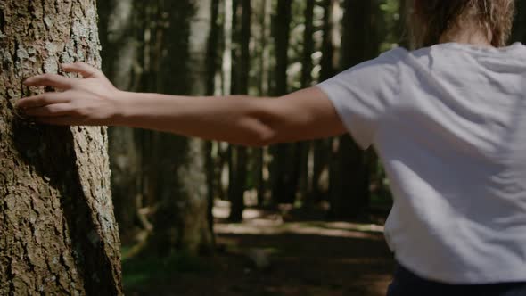 Woman with dreadlocks Touching large pine tree in forest and running into forest.