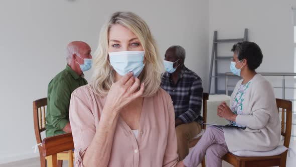 Two diverse senior couples sitting in circle having therapy conversation at home looking at camera