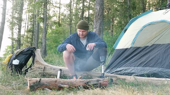 Disabled tourist is warming himself by the fire with a tent