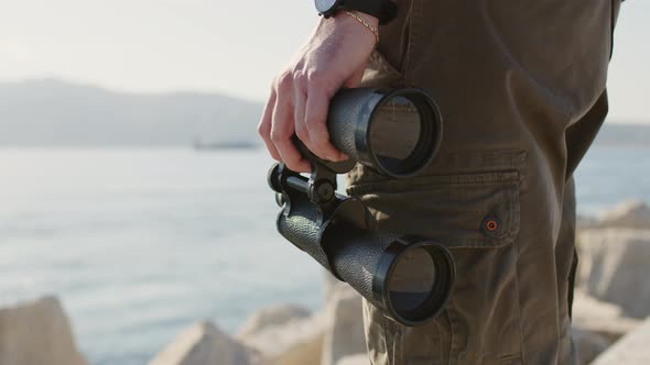 Binoculars in Hands with Sea Background