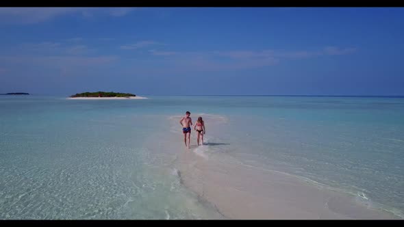 Young couple happy together on relaxing coastline beach trip by aqua blue lagoon and white sandy bac