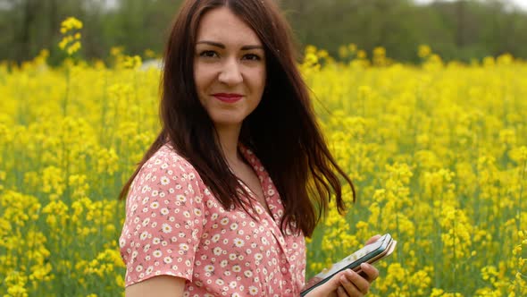 A beautiful cheerful young girl takes pictures of herself on the phone in a field