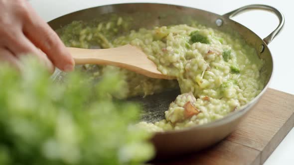 Faceless chef serving risotto on plate