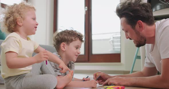 Close Up of a Little Boy and a Little Girl and Their Father are Drawing with Pencils on the White