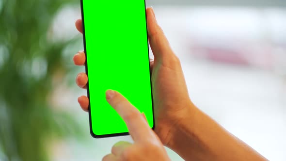 Woman at Home Using Smartphone with Green Mockup Screen in Vertical Mode