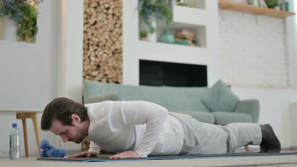 Young Man Doing Pushups on Yoga Mat at Home