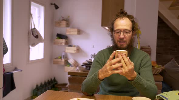 Father typing on a cell phone during the morning at the kitchen.