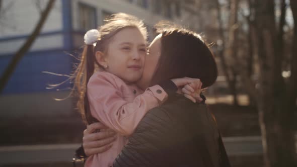 Mother Hugging and Kissing a Little Daughter After School