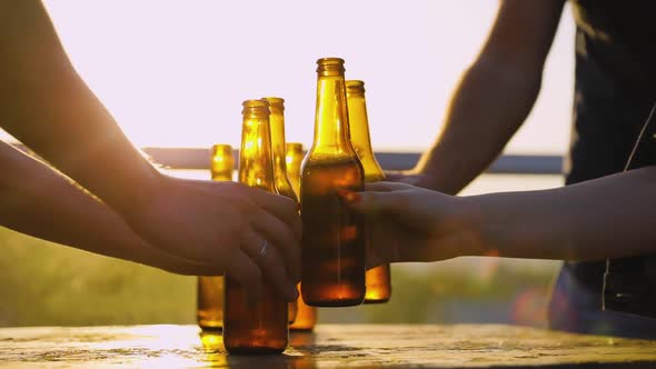 Friends Drinking Beer Outdoors. Bottles In Hands Closeup