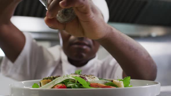African american male chef garnishing dish in restaurant kitchen