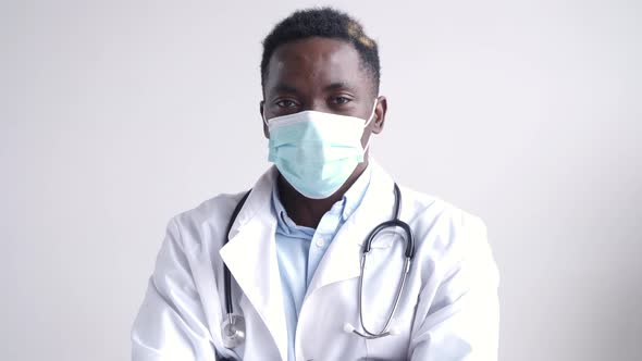 African Black Male Doctor Wears Face Mask Looking at Camera with Arms Crossed
