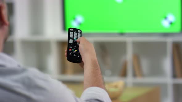 Man Using Remote Control while Watching Green Screen TV