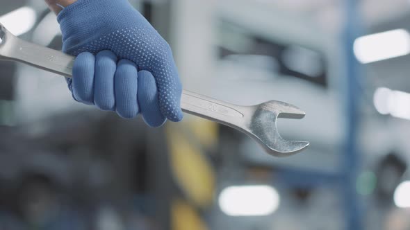 Closeup of Male Caucasian Hand in Working Glove Holding Adjustable Wrench