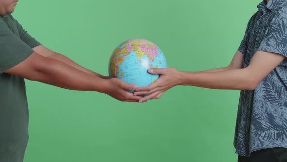 Man Hand In The World Globe To Another Man While Standing In Front Of Green Screen Background