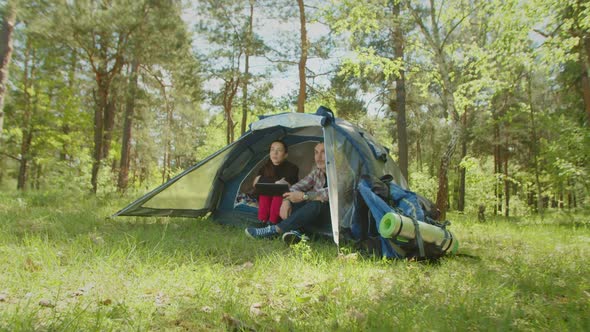 Relaxed Hiker Couple Networking on Tablet Pc in Camp Tent