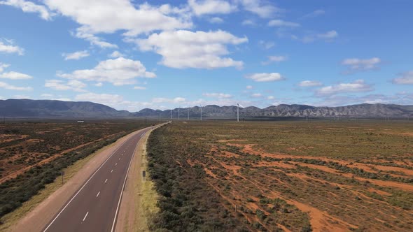 Drone aerial flying up and forward in Australian outback desert country road with renewable energy w