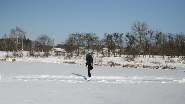 Young woman in skirt and white figure skates is ice skating on ice