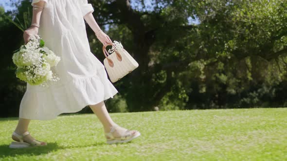 RED Camera Slow Motion Woman Walking with Straw Bag and Flowers in Green Park