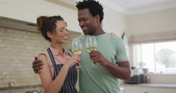 Happy biracial couple cooking together, drinking wine