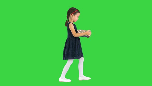 Little Girl in Black Dress Walking with a Gift Box in Her Hands on a Green Screen Chroma Key