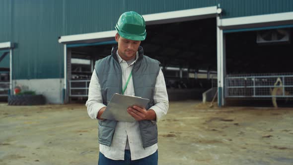 Supervisor Engineer Holding Clipboard Making Notes at Modern Cowshed Building