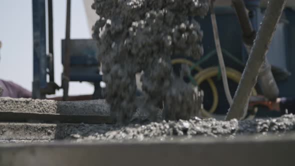 Workers pouring concrete into large steel molds on a construction site