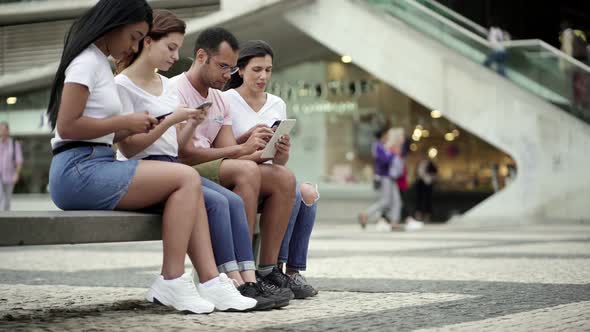 Calm People Sitting on Bench with Modern Devices