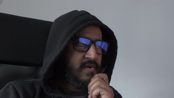 Adult Male Wearing Hoodie And Glasses Talking On Microphone Earphone Swiveling On Chair. Locked Off