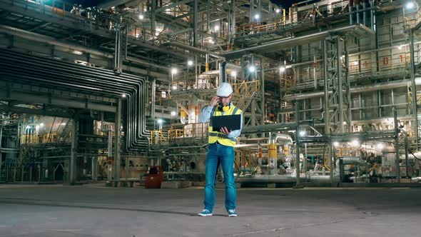 Male Expert is Using a Laptop on the Premises of the Refinery Plant